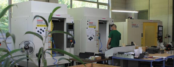 Ein Foto während eines Arbeitsalltags in unserer Fräsabteilung, Fanuc CNC Maschinenpark, Serienfertigung eines Mitarbeiters der die Maschine einrichtet